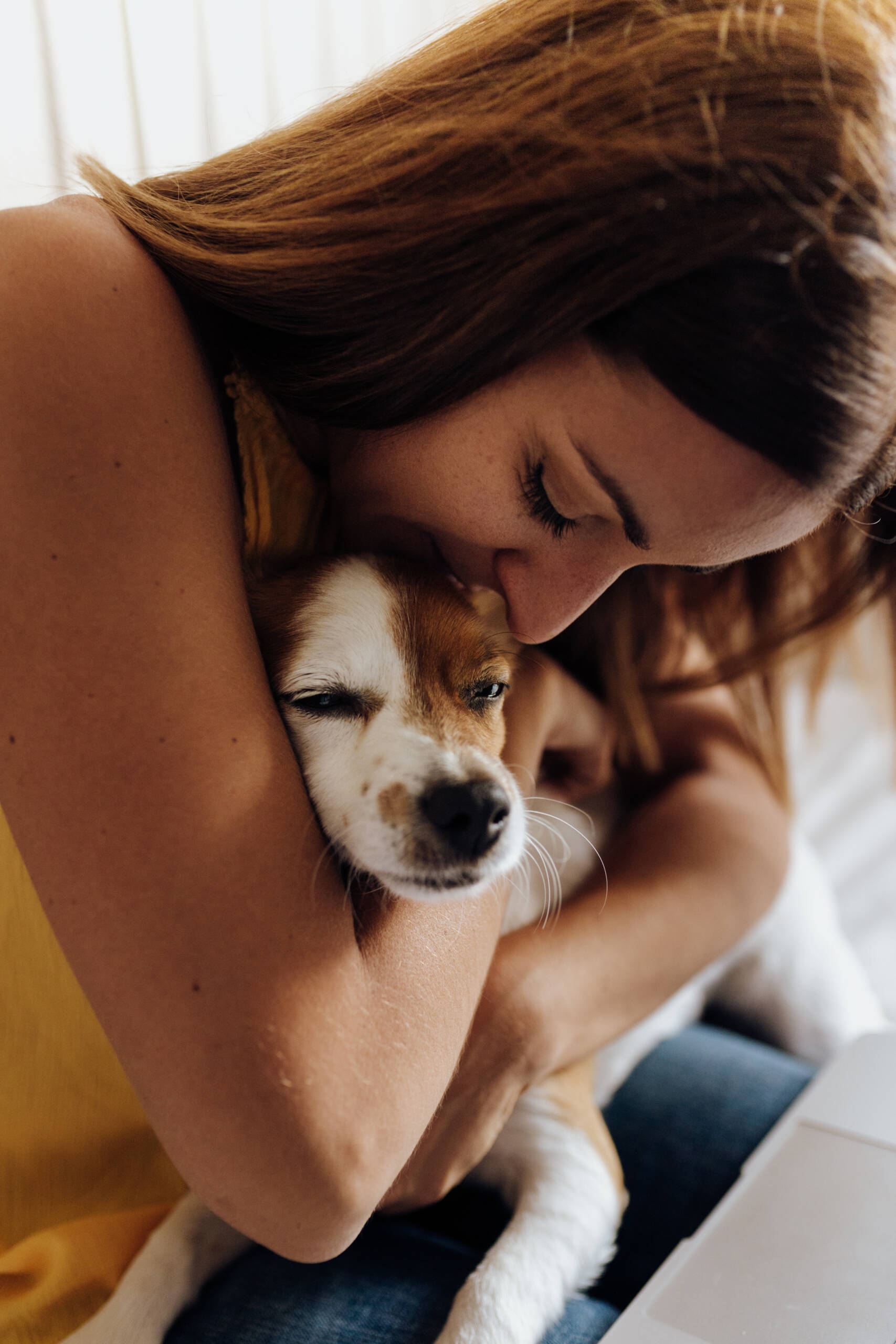 Nahaufnahme einer schönen Frau, die ihren Hund Jack Russell Terrier bei Sonnenuntergang küsst