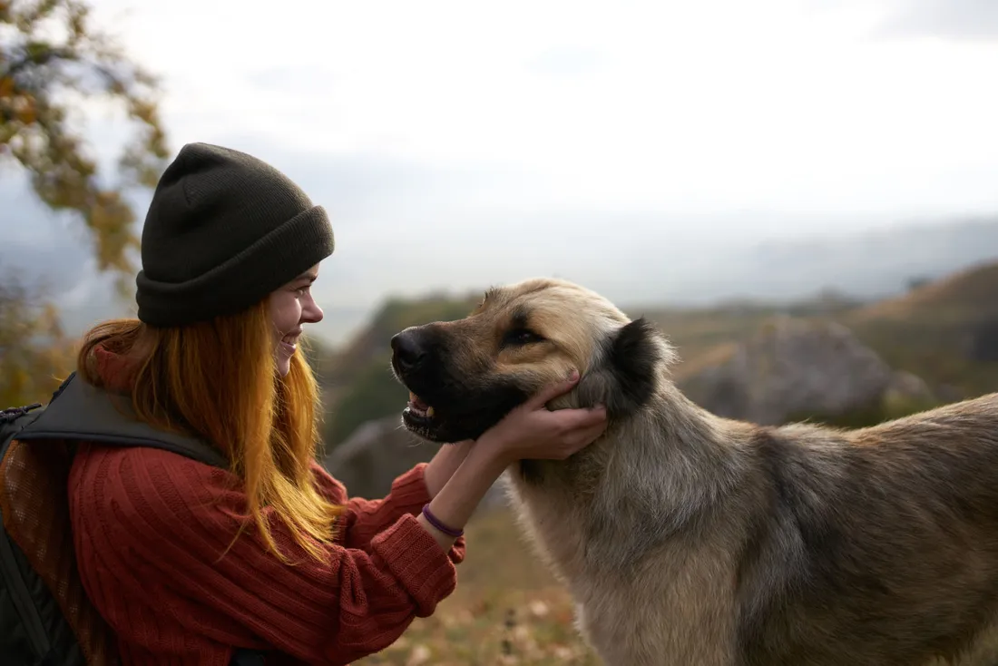 Frau kniet bei ihrem Hund im Wald
